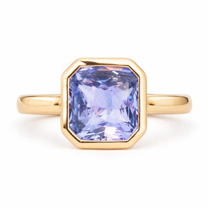 Antique-inspired lavender sapphire solitaire engagement ring in yellow gold, featuring a square emerald-cut stone in a geometric rub-over setting.