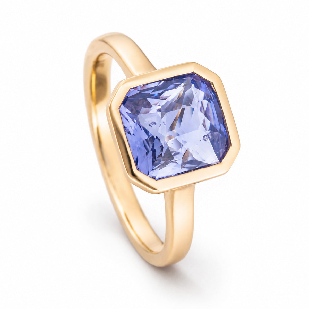 Elevated studio portrait of the sapphire ring, showcasing its cut-cornered setting and slender polished gold band.