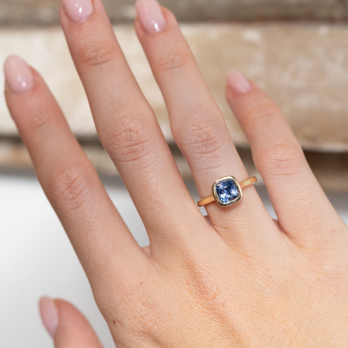 Blue sapphire engagement ring worn on a hand, showcasing its rich blue gemstone and elegant proportions.