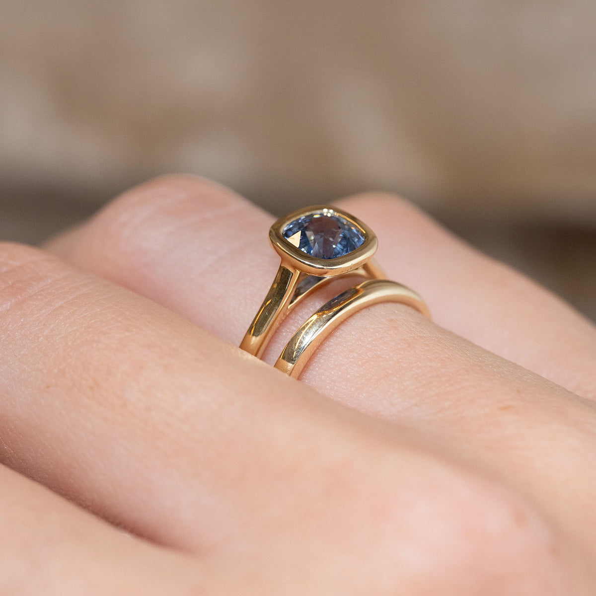 Side-angle view of the blue sapphire solitaire ring paired with a wedding band, showcasing its wed-fit design for a flush-fitting wedding ring.