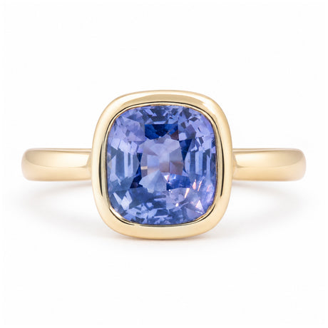 Antique-inspired colour-change sapphire solitaire engagement ring in yellow gold, featuring a cushion-cut blue-violet gemstone in a smooth bezel setting.