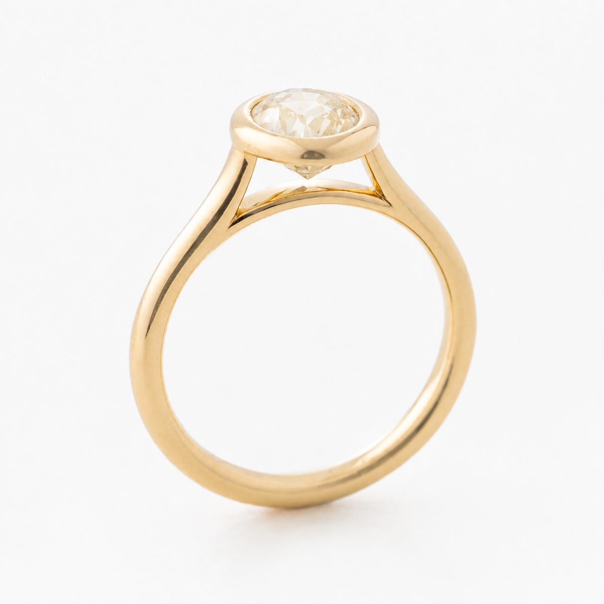 A vintage-inspired yellow gold engagement ring with a pale yellow oval sapphire.