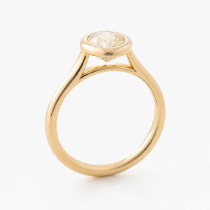 A vintage-inspired yellow gold engagement ring with a pale yellow oval sapphire.