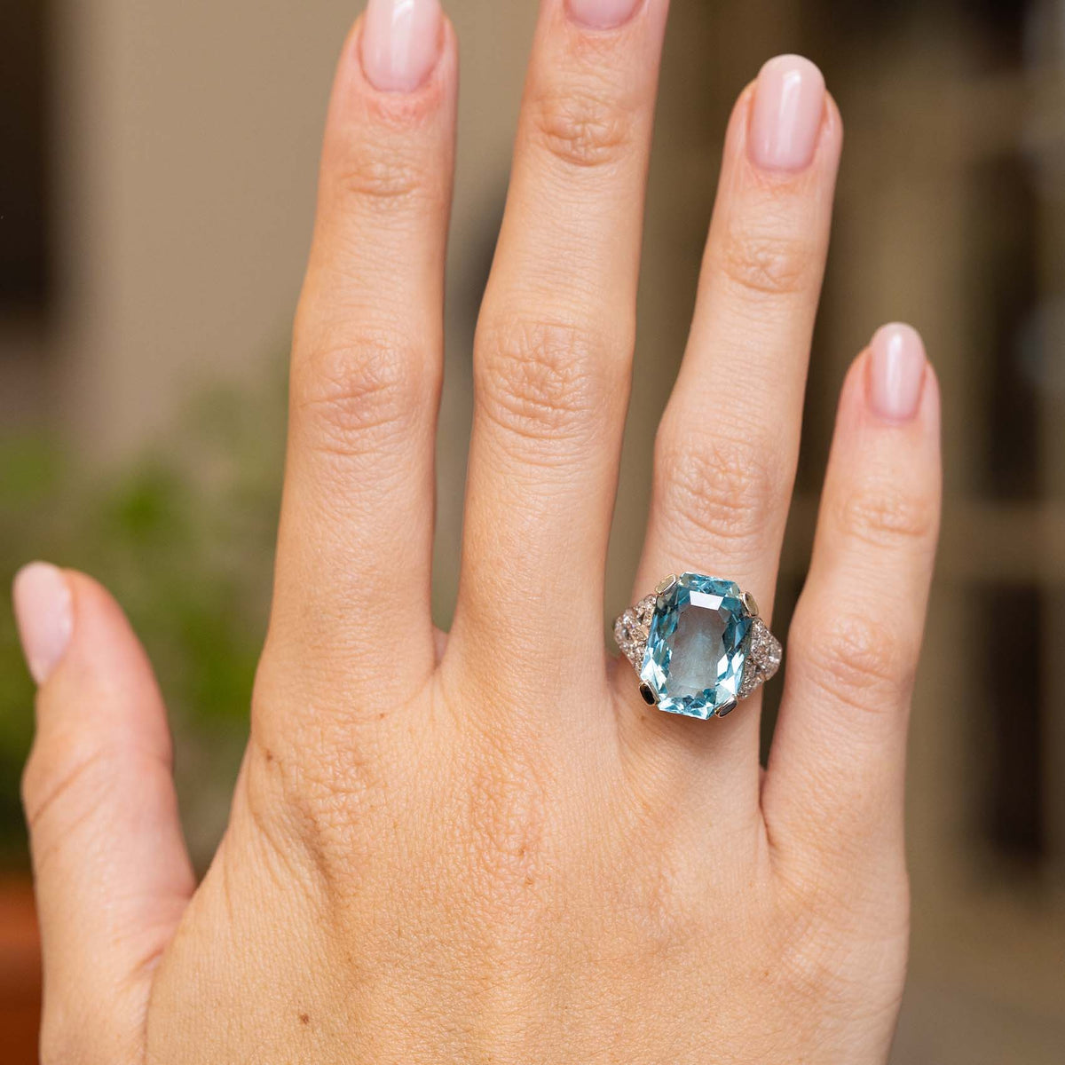 Full-hand view of an antique Art Deco cocktail ring with an octagonal blue aquamarine and round diamonds set in platinum.