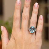 Full-hand view of an antique Art Deco cocktail ring with an octagonal blue aquamarine and round diamonds set in platinum.