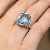 Antique Art Deco aquamarine cocktail ring worn on the hand, with sparkling round diamonds set into decorative platinum shoulders.