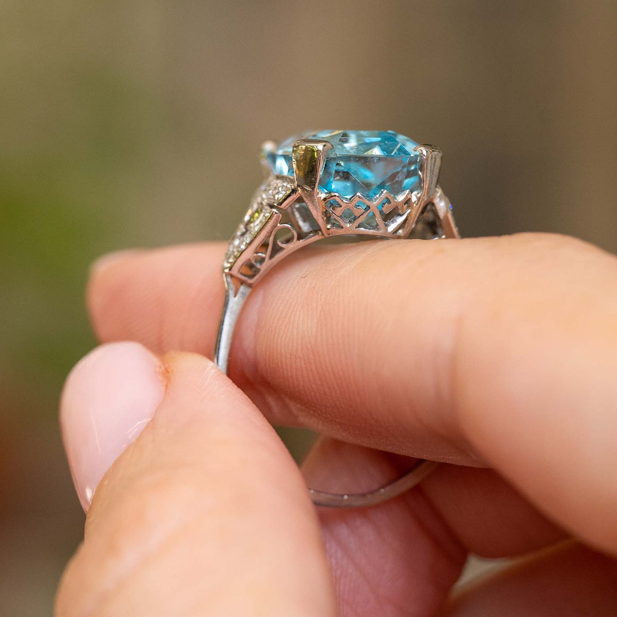 Profile view of an antique aquamarine and diamond ring, revealing the raised platinum setting and ornate openwork gallery.