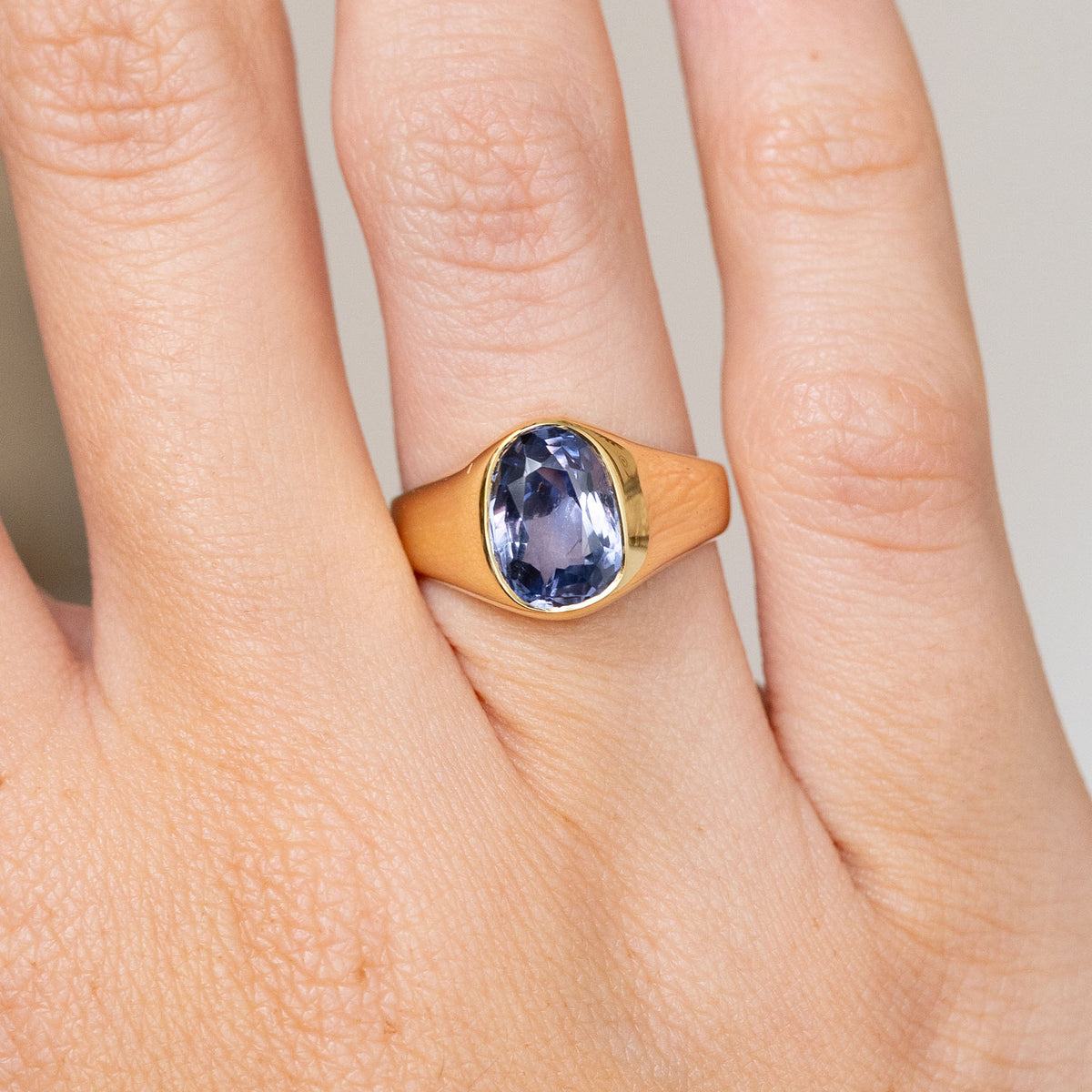 Close-up of the antique yellow gold ring, featuring a blue-violet sapphire within a smooth rub-over setting.