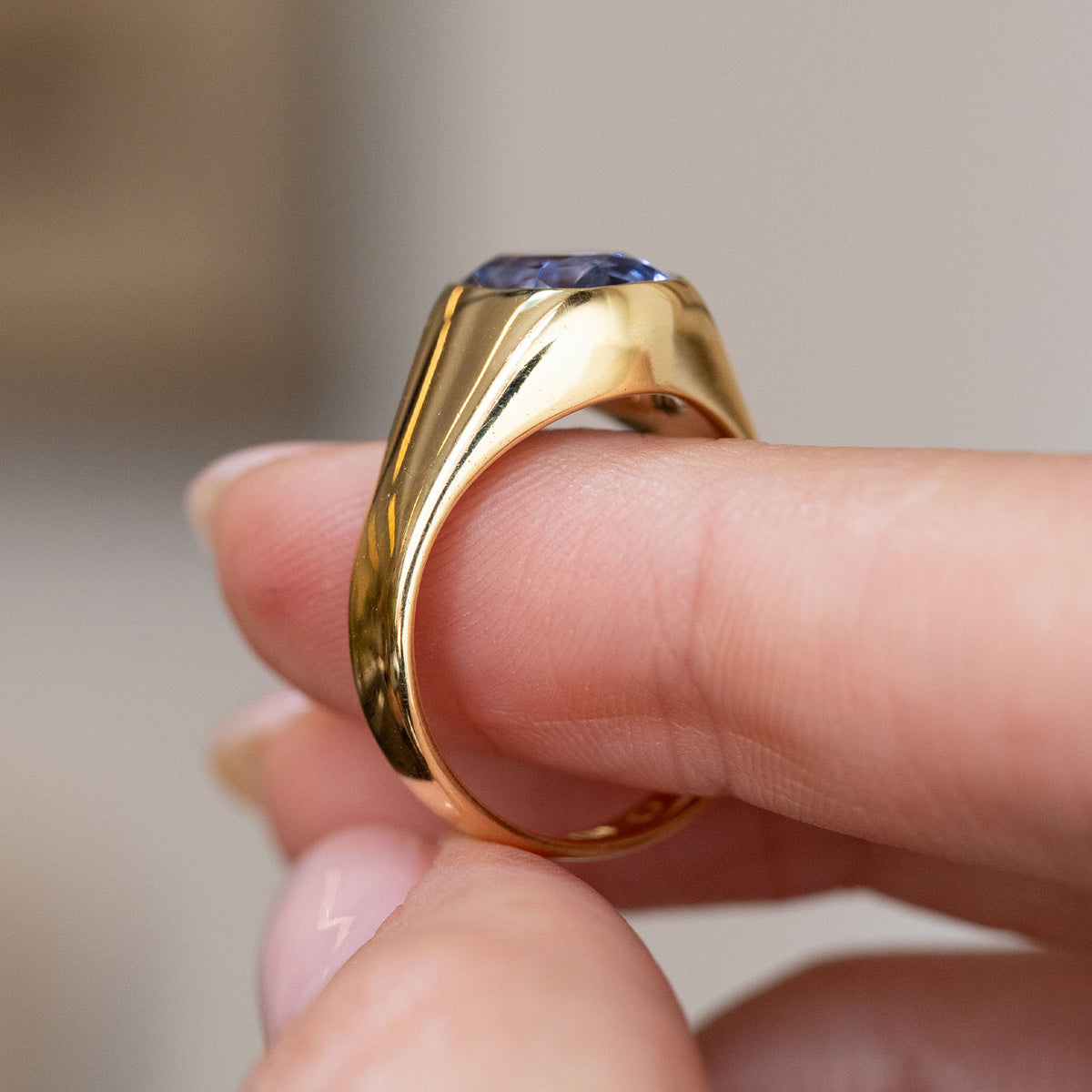 Side view of the yellow gold sapphire ring, revealing its gently elevated setting and smoothly tapered shoulders.