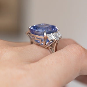 Side view on the hand highlighting the raised sapphire setting and intricate geometric platinum gallery.