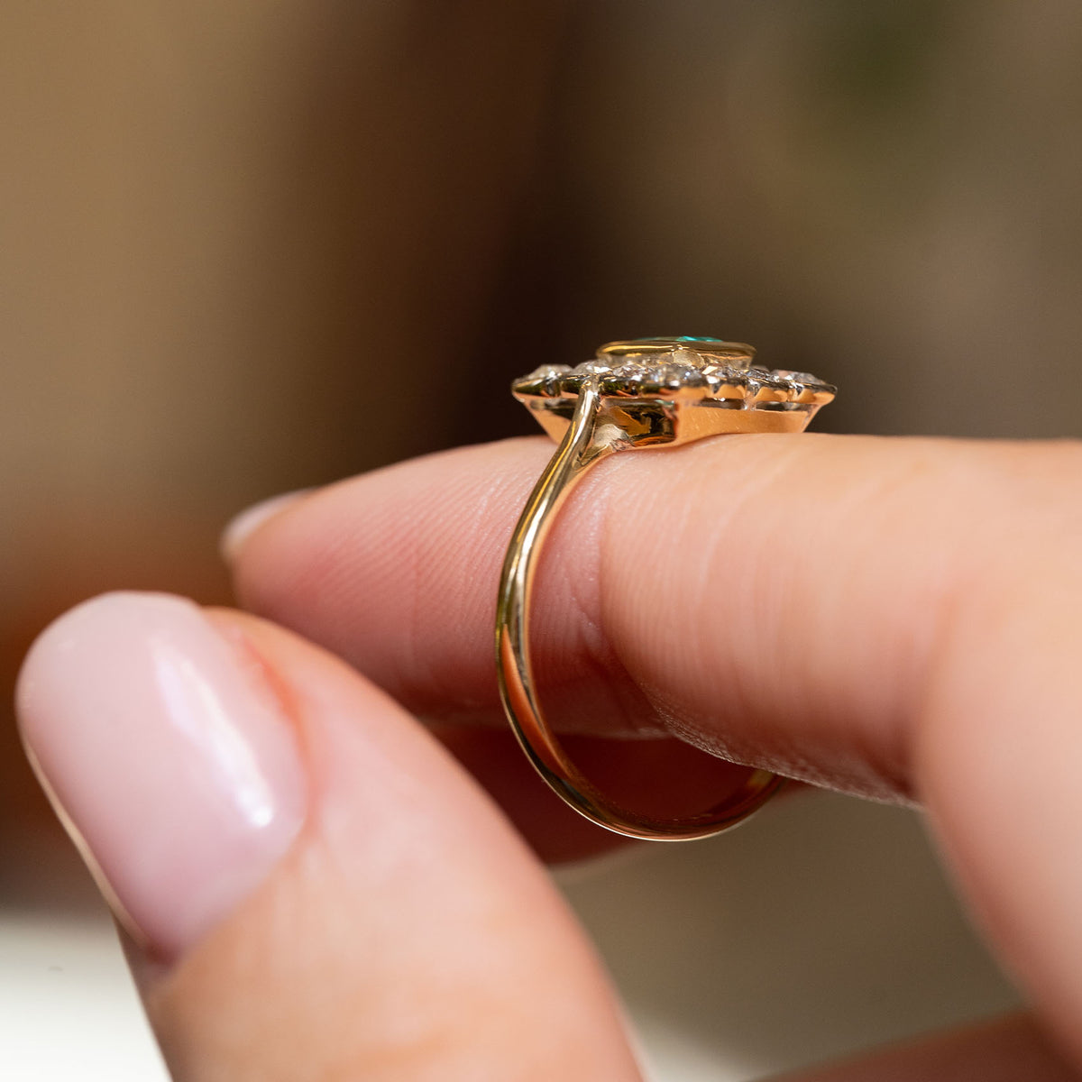 Profile view of an antique Edwardian cluster ring, revealing the raised platinum setting and slender yellow gold band.