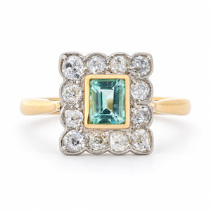Front view of an antique Edwardian engagement ring featuring a mint green step-cut emerald and old-mine cut diamond cluster in yellow gold and platinum.