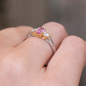 A photo of a Vintage 1990s three-stone engagement ring with a yellow gold setting mounted on a platinum band, worn on the finger and shown from the side to display the ring's profile.