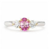 Vintage, 1990s pink sapphire and diamond three-stone engagement ring in platinum shown against a white background.