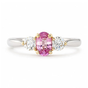 Vintage, 1990s pink sapphire and diamond three-stone engagement ring in platinum shown against a white background.