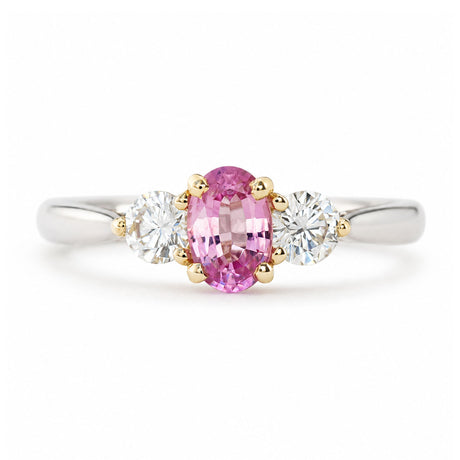 Vintage, 1990s pink sapphire and diamond three-stone engagement ring in platinum shown against a white background.