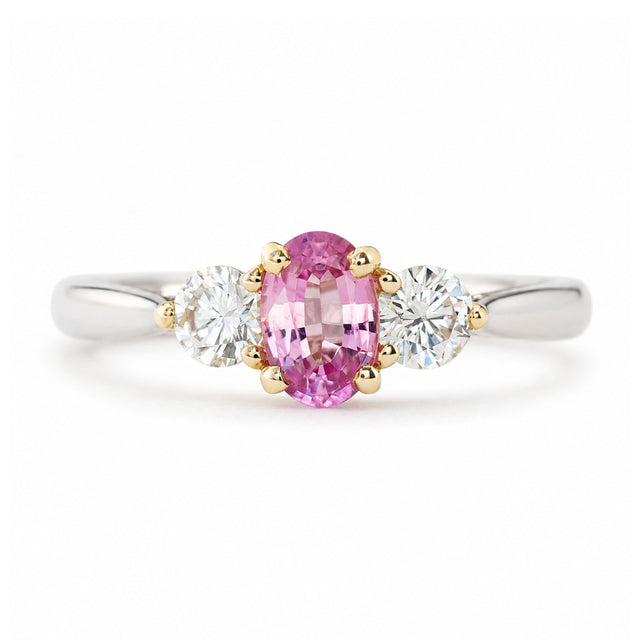 Vintage, 1990s pink sapphire and diamond three-stone engagement ring in platinum shown against a white background.