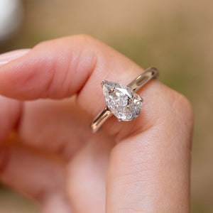 Vintage salt and pepper diamond engagement ring worn on a finger, showcasing the stone’s unique natural inclusions and pear shape.
