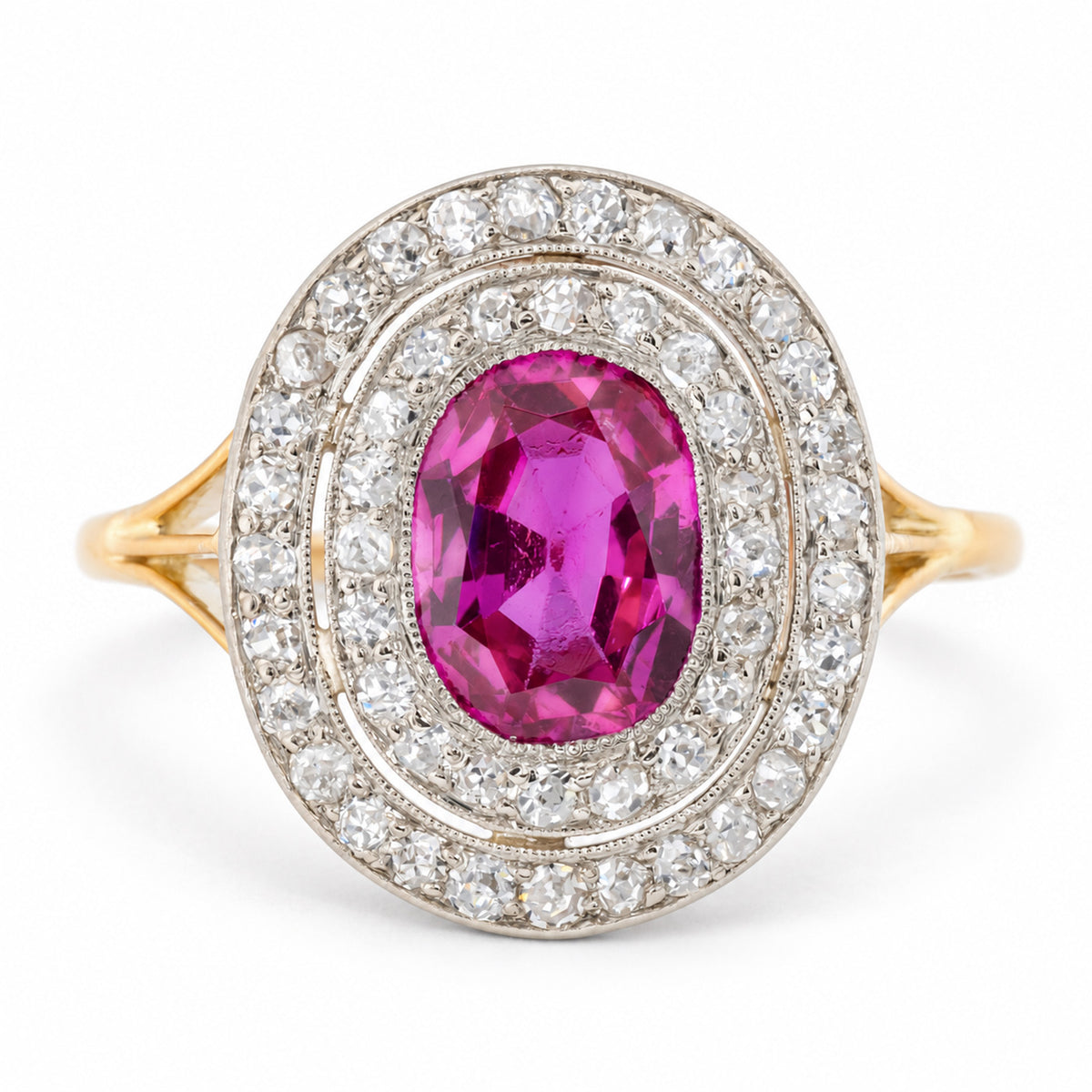 Antique Edwardian Burmese ruby and diamond cluster engagement ring in yellow gold and platinum, featuring an oval old-cut pinkish-red ruby surrounded by two concentric halos of sparkling diamonds.