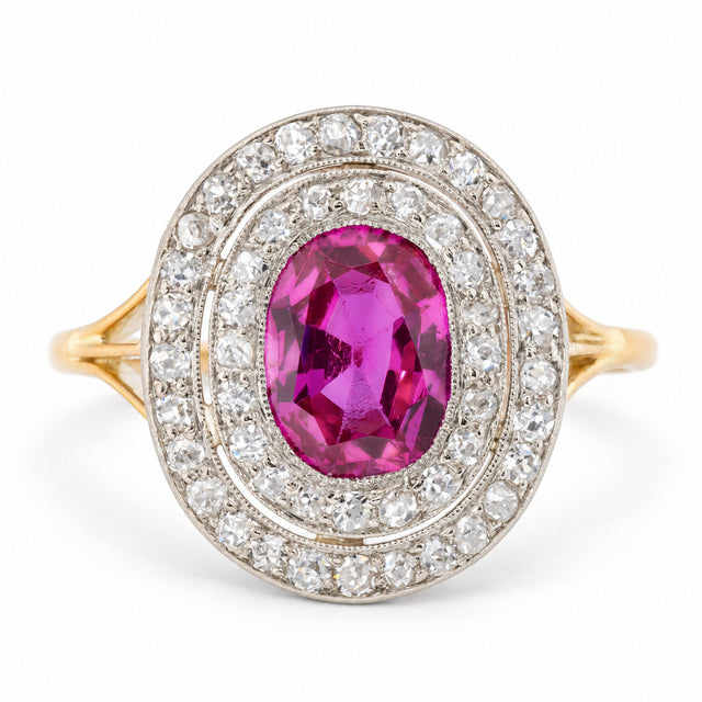 Antique Edwardian Burmese ruby and diamond cluster engagement ring in yellow gold and platinum, featuring an oval old-cut pinkish-red ruby surrounded by two concentric halos of sparkling diamonds.