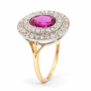 Angled view of an antique Edwardian Burmese ruby and diamond cluster ring, highlighting its oval ruby, intricate platinum double diamond halo and raised yellow gold setting.