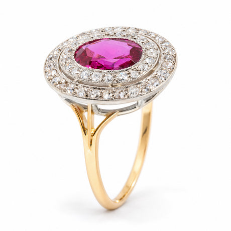 Angled view of an antique Edwardian Burmese ruby and diamond cluster ring, highlighting its oval ruby, intricate platinum double diamond halo and raised yellow gold setting.
