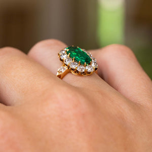 A close up of the side profile of an Antique, Belle Époque Colombian emerald and diamond cluster engagement ring. Showing the profile of the ring once worn, the yellow gold band and shoulder details.  