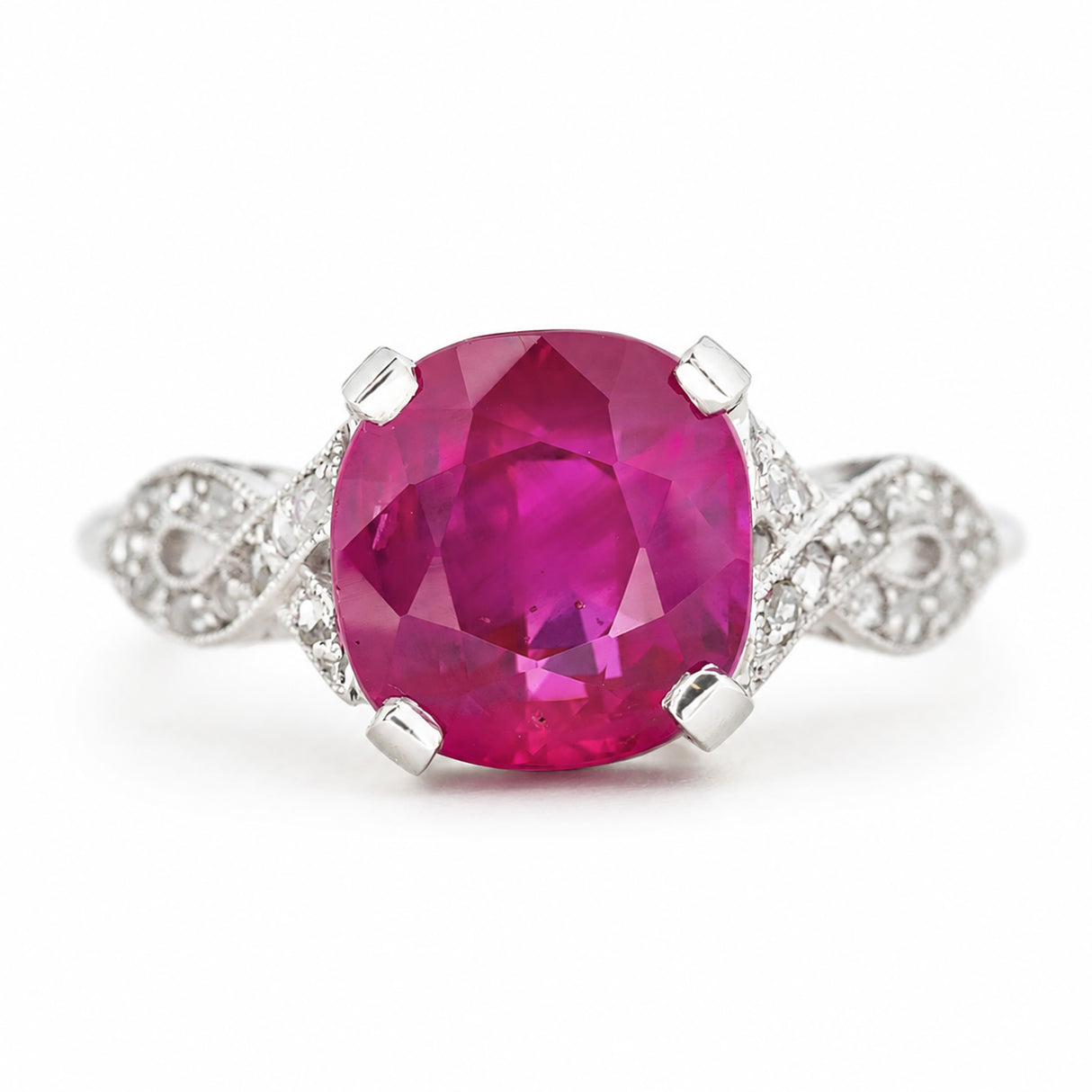 A cushion-cut Burmese pink ruby Art Deco engagement ring with pavé diamonds set either side into the white gold band. Shown on a plain white background. 