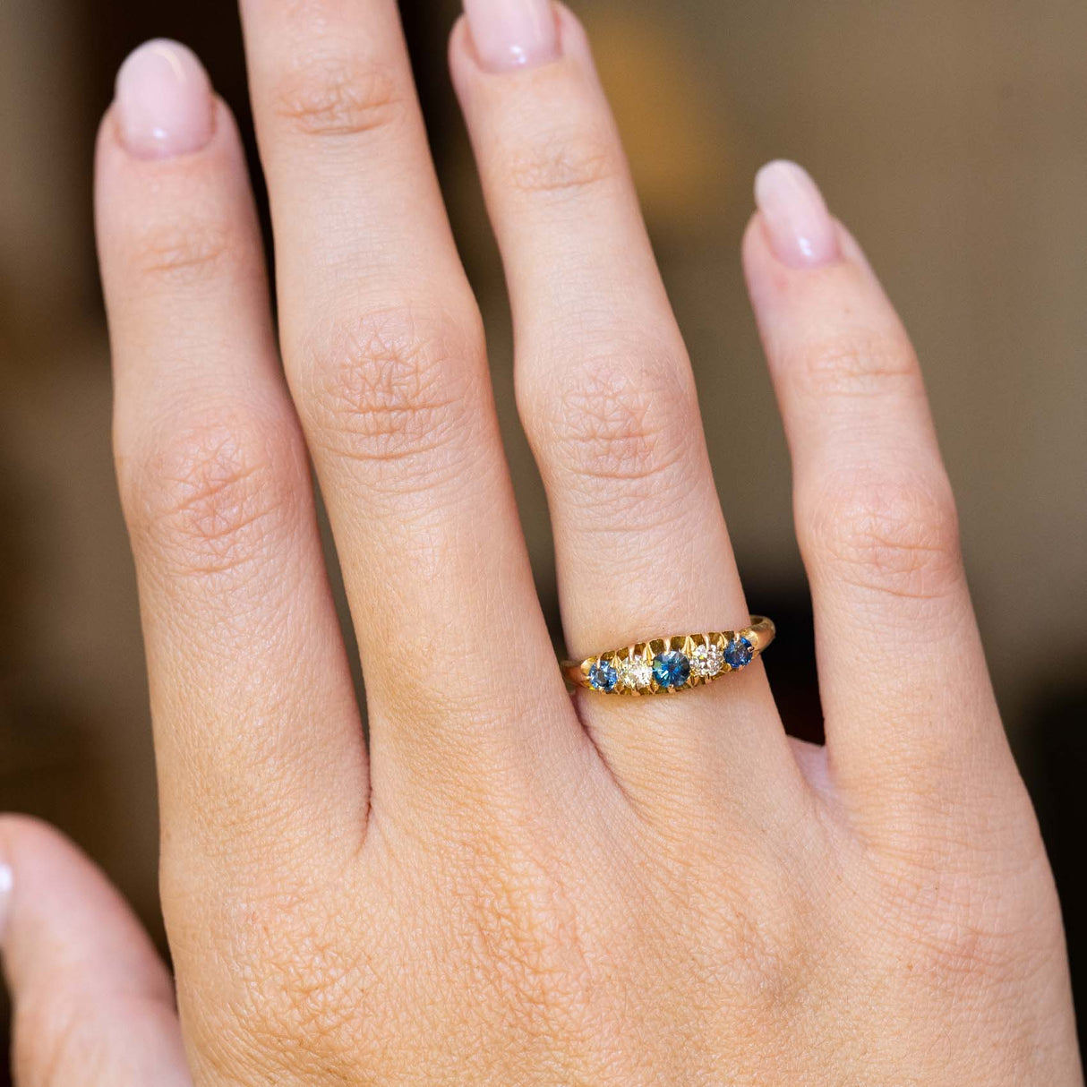 An antique Edwardian blue sapphire and diamond five-stone ring worn on the hand.