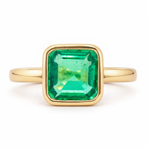 Antique-inspired Colombian emerald solitaire engagement ring in yellow gold, featuring a square emerald-cut stone in a smooth rub-over setting.
