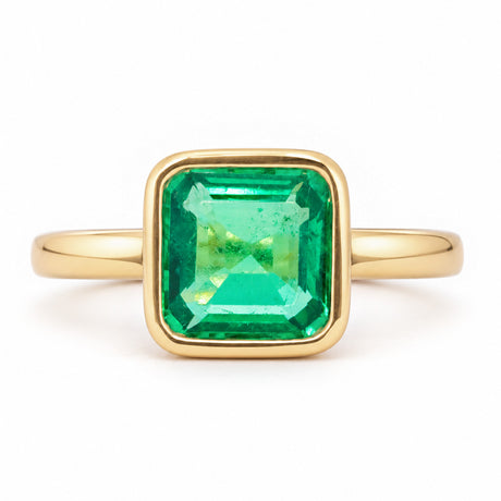 Antique-inspired Colombian emerald solitaire engagement ring in yellow gold, featuring a square emerald-cut stone in a smooth rub-over setting.