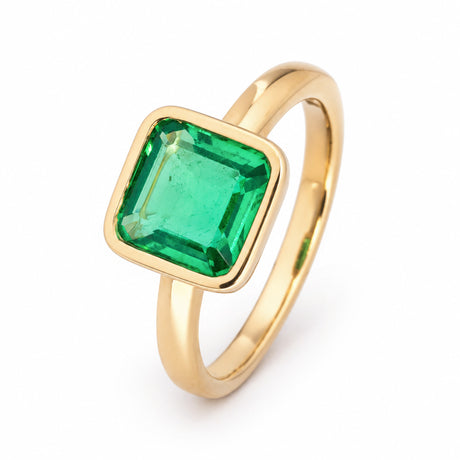 Three-quarter studio view of a square-cut Colombian emerald ring, highlighting its vivid green colour and polished yellow gold band.