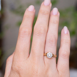 An image of an outstretched hand wearing an antique yellow gold engagement ring designed as a diamond cluster, worn on the finger to show the proportions.