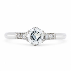 An antique ring from the Art-Deco period featuring a diamond at the centre flanked by smaller diamonds on the shoulders set in platinum.