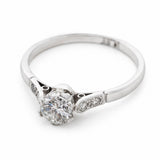 A three-quarter view of an  Art-Deco platinum ring set with a natural round diamond at the centre.  