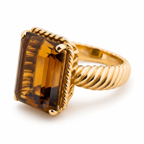A gold Cartier cocktail ring featuring a large, rectangular faceted amber-brown smoky quartz in a twisted rope-style bezel setting, shown on a clean white background.