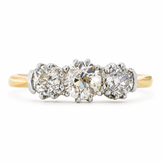 An antique, Edwardian engagement ring with three old-cut diamonds with a yellow gold band. 