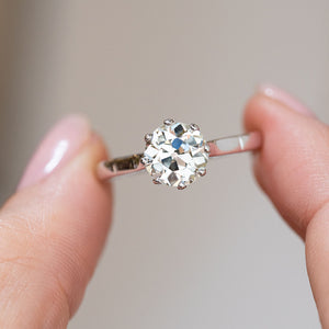 Warm old-cut diamond ring held between the fingers, offering a detailed look at its broad facets and antique charm.