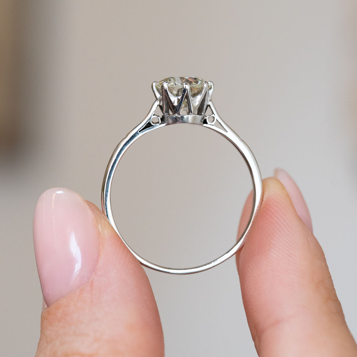 Profile of the platinum engagement ring, showing its elevated basket setting and finely tapered band.
