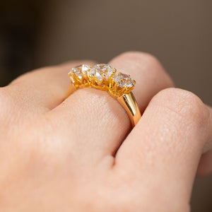 Side view of a vintage three-stone diamond ring worn on the hand, showing the raised claw setting and tapered 18ct yellow gold shoulders.