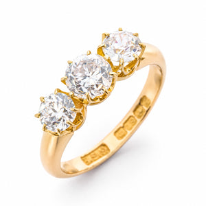 Angled product view of a vintage 18ct yellow gold engagement ring featuring three graduated claw-set diamonds of mixed antique cuts.