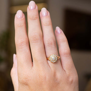 An outstretched hand wearing an antique Victorian era yellow gold old-cut diamond coronet cluster engagement ring, seen from a distance to show its proportions and scale.