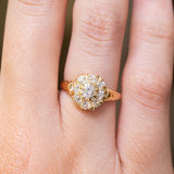 A close-up of a hand wearing an antique Victorian era yellow gold old-cut diamond coronet cluster engagement ring.
