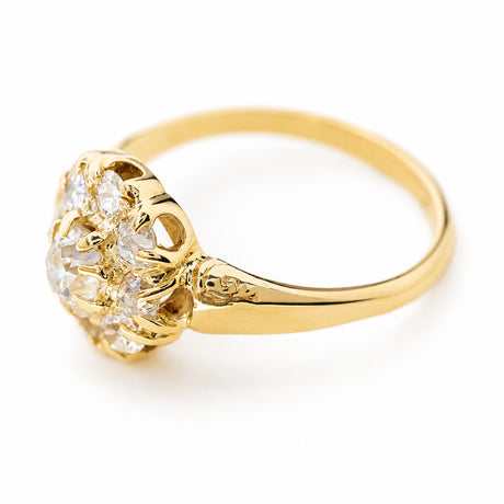 A Victorian old cut diamond cluster engagement ring in yellow gold shown at an angle against a plain white background to showcase the claw setting style and gallery.