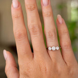 A hand wearing an Antique, Edwardian diamond platinum trilogy engagement ring.