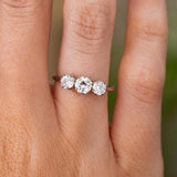 A close-up of a hand wearing an Antique, Edwardian diamond trilogy engagement ring made in platinum.