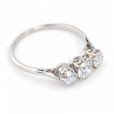 A three-quarter top view of an antique platinum engagement ring set with three old-cut diamonds.
