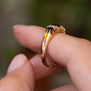 Side profile of an Antique, Edwardian blue sapphire and diamond five-stone engagement ring displaying the detailing on the shoulders and the low profile of the ring and yellow gold band. 