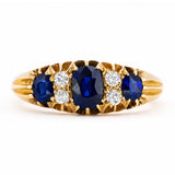 An Antique, Edwardian sapphire and diamond five-stone engagement ring in yellow gold shown against a plain white background