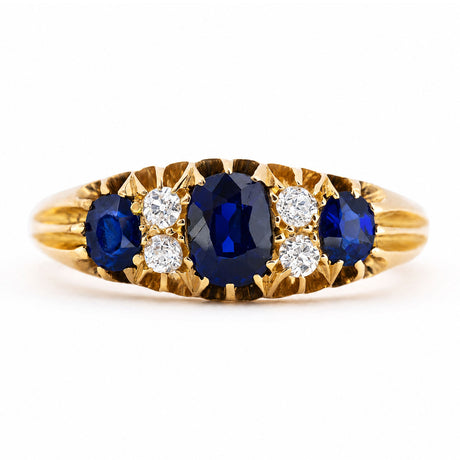 An Antique, Edwardian sapphire and diamond five-stone engagement ring in yellow gold shown against a plain white background